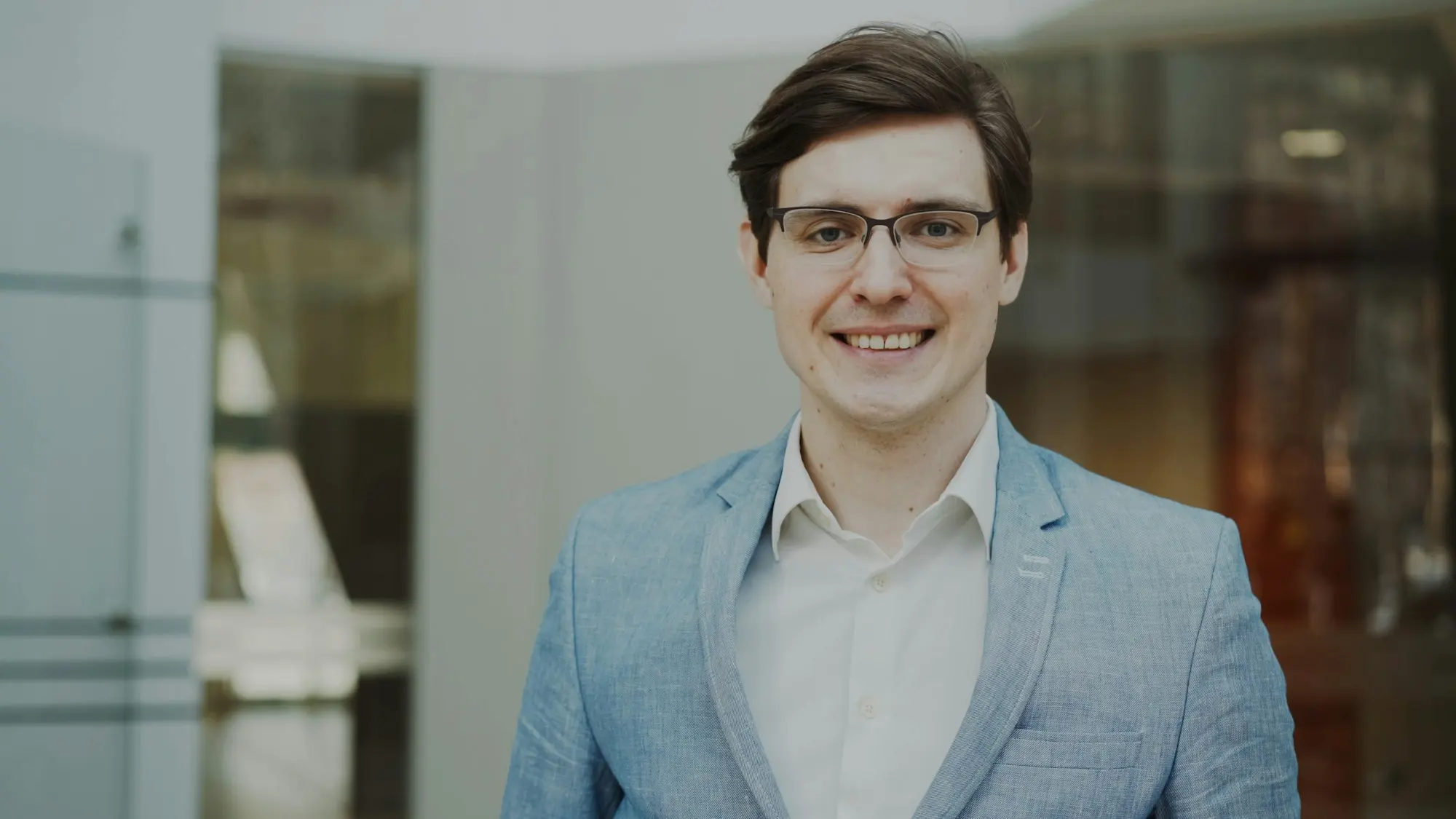 Theo Marsh, in glasses and a light blue jacket, smiling