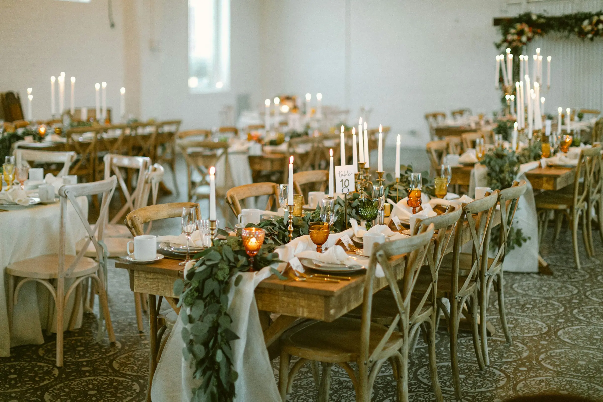The Freight Room set for supper: pine farm tables, oak crossback chairs, brass candlesticks and amber glass along limewashed brick walls