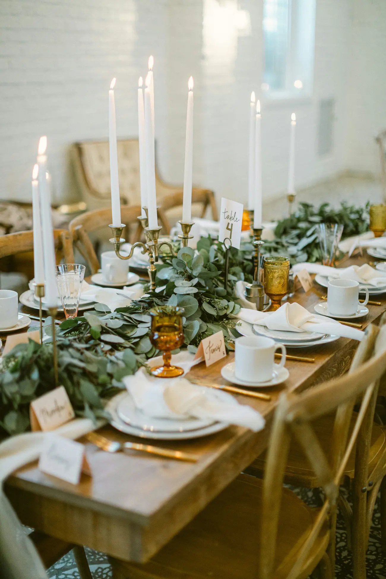 Brass candlesticks and white tapers down a long table
