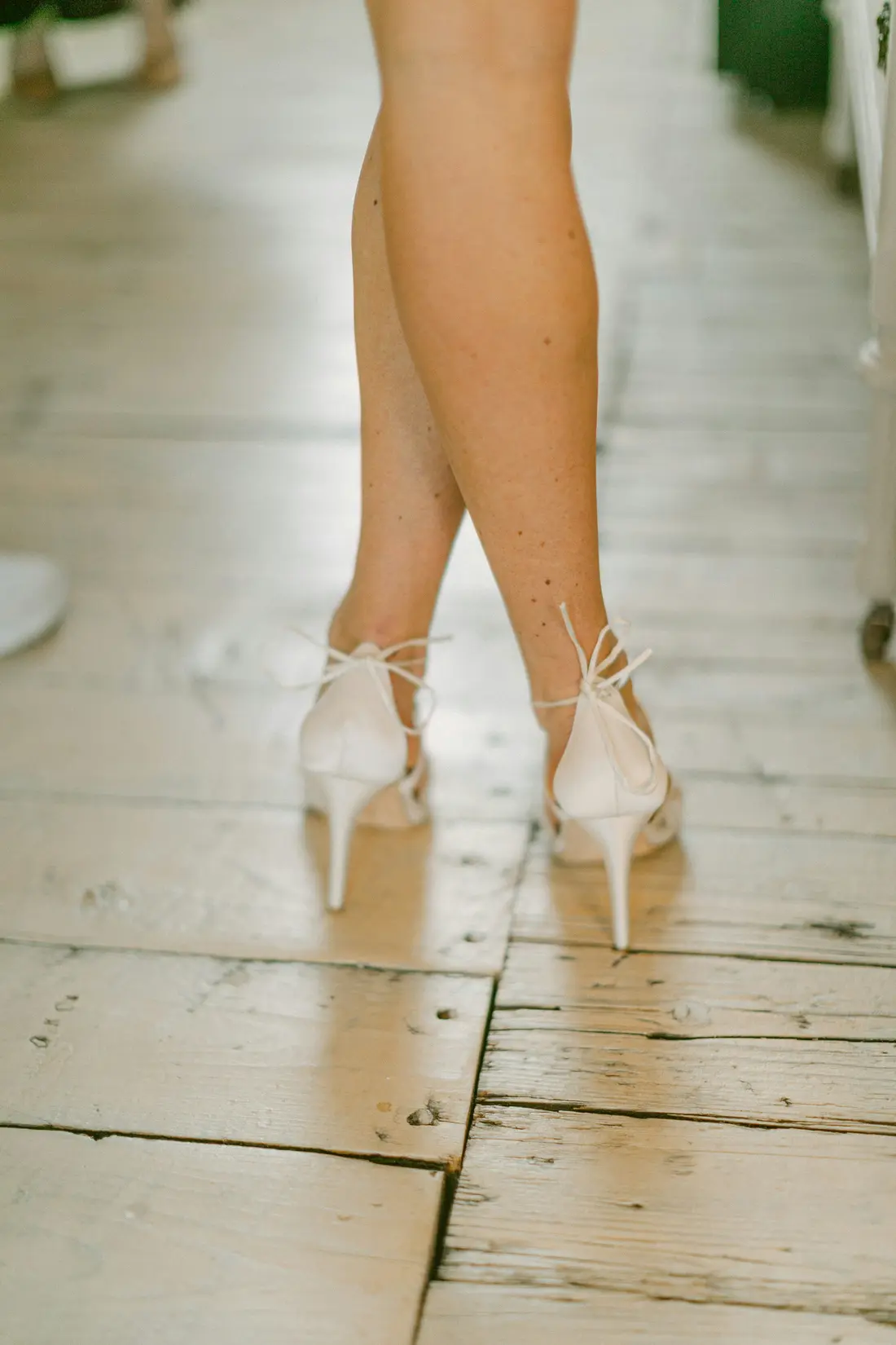 A bridesmaid's ivory heels on the worn original pine floorboards