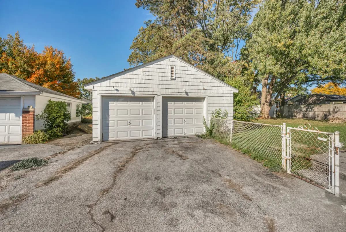 A detached two-car garage at the end of a long concrete driveway